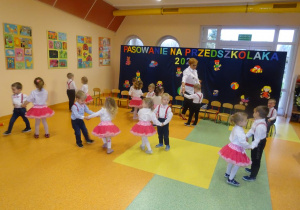 Dzieci ustawione w parach na przeciwko siebie, tańczą. Pani dyrektor Maria Królikowska tańczy z w parze z chłopcem.